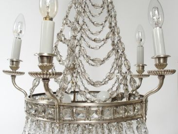 Lustre à quatre lumières à armature en métal nickelé enserrant des chu