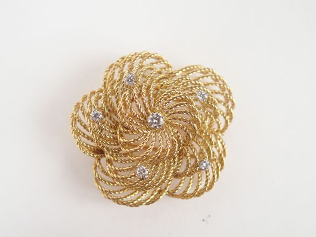 Broche en or jaune ajouré en forme de fleur rehaussée de brillants. Po