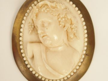 Broche XIXe en ivoire sculpté figurant Bacchus jeune. Monture en laito