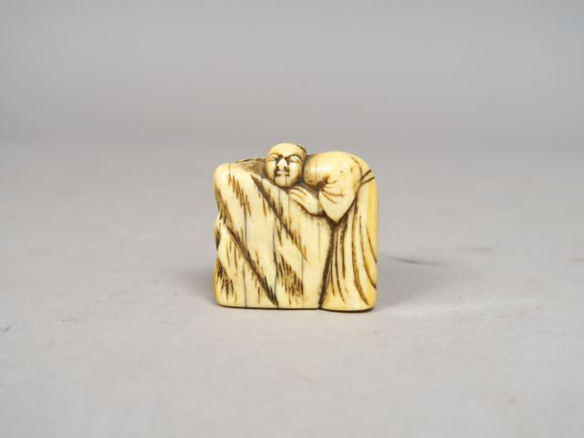 Netsuke en ivoire représentant un personnage debout contre un rocher s