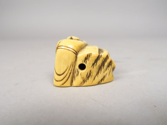 Netsuke en ivoire représentant un personnage debout contre un rocher s