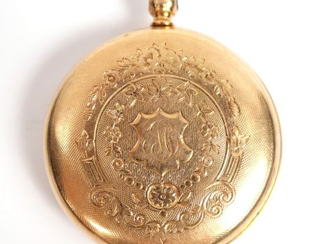 Montre de col en or jaune, à décor gravé de fleurs, monogrammée. Poids