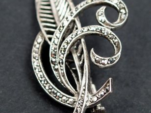 Broche en argent, en forme de plume et de volutes, pavée de strass. 6c