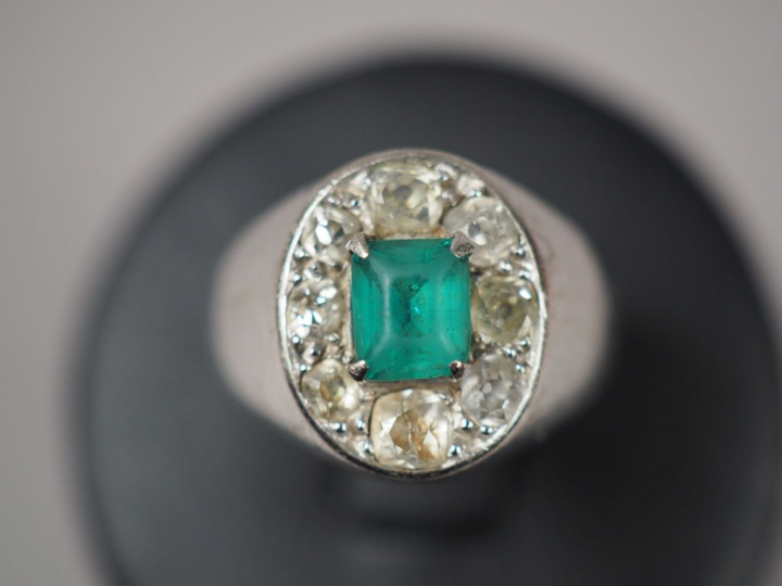 Bague chevalière en or blanc, ornée d'une émeraude entourée de roses. 