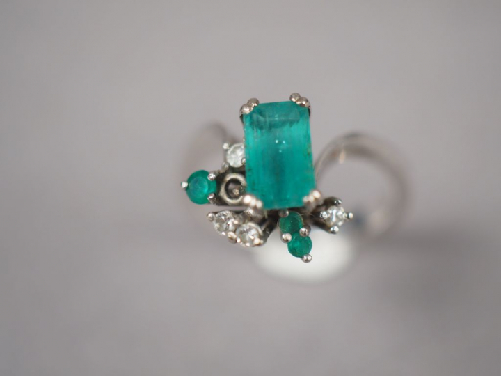 Bague en or blanc, ornée en son centre d'une émeraude entouré de quatr