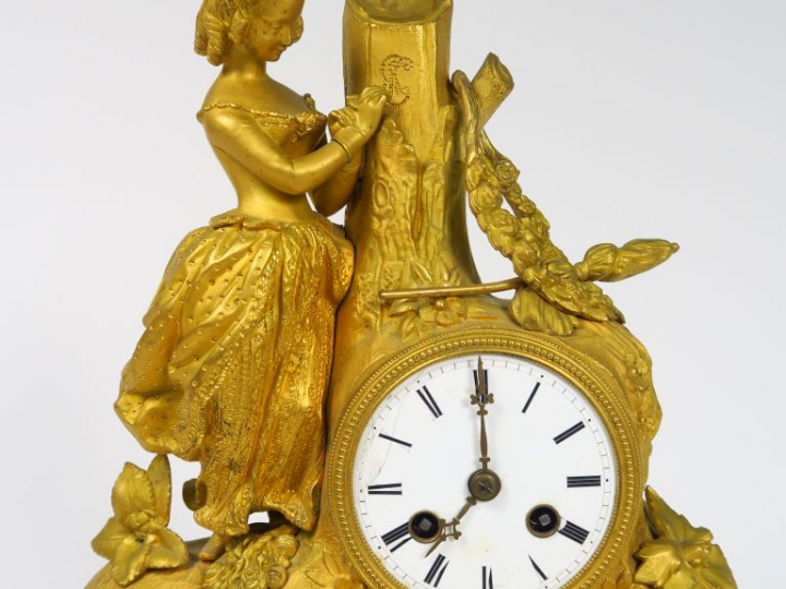 Pendule Restauration en bronze doré à décor de jeune fille romantique.