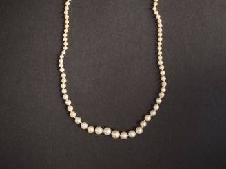 Vente aux enchères Collier de perles fines disposées en chute.  Joli fermoir en or blanc 