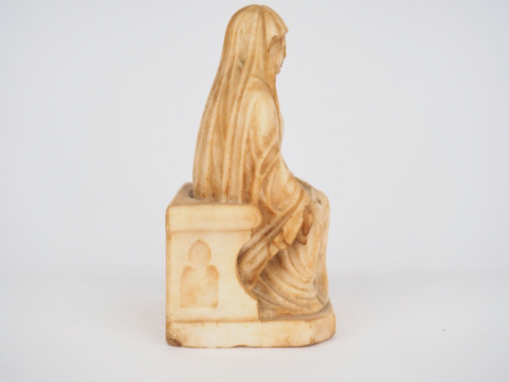 Vierge en albâtre sculpté en ronde-bosse. Assise sur un banc-trône orn