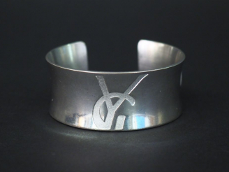 Vente aux enchères 	Bracelet manchette en argent, à décor d’un monogramme.  Poids. 57 g