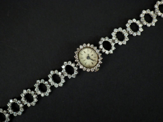 Vente aux enchères 	Montre bracelet de dame en or blanc et diamants. Cadran ovale à index