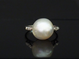 Vente aux enchères Bague en or blanc, sertie en son centre d'une perle blanche épaulée de