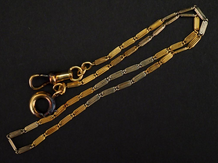Giletière deux tons d'or, composée de maillons, à décor d'enroulement.