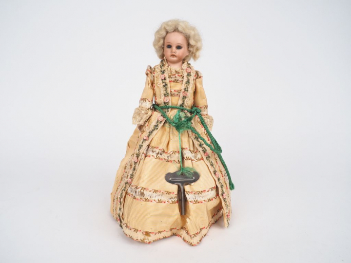 Poupée mécanique, tête porcelaine. H. 29 cm (usures et accidents à la 