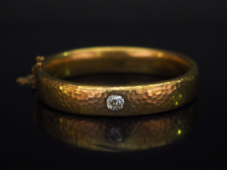 Vente aux enchères Bracelet jonc en or jaune martelé, serti en son centre d'un diamant ta