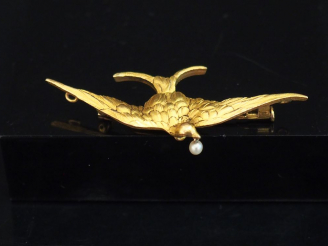 Vente aux enchères Broche en or jaune, figurant un oiseau aux ailes déployées tenant dans