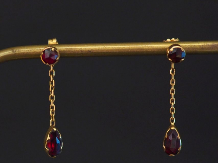 Paire de perce-oreilles en or jaune, sertis de deux grenats dont un en