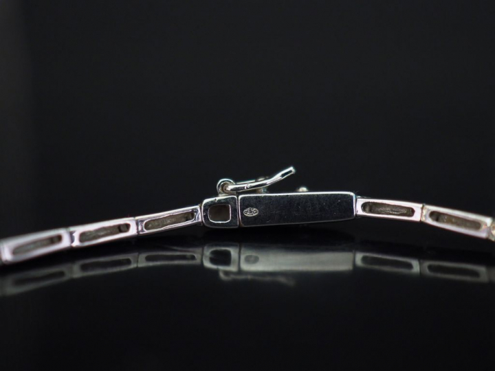 Collier articulé en or blanc, à décor en son centre d'un nœud de ruban