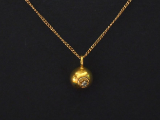 Vente aux enchères Pendentif en or jaune en forme de boule sertie d'un petit éclat de dia