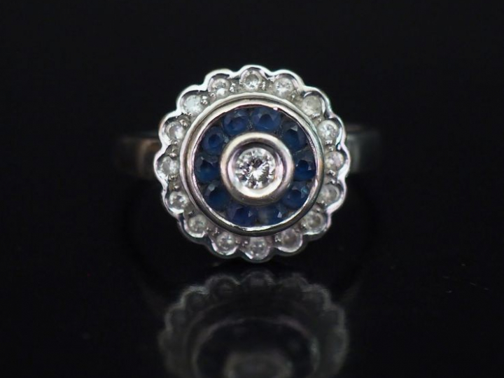 Bague ronde en or blanc, sertie en son centre d'un diamant entouré d'u
