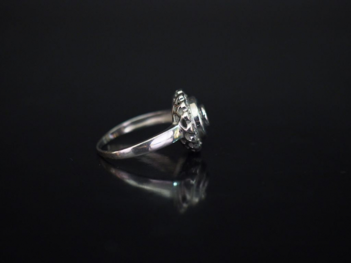 Bague ronde en or blanc, sertie en son centre d'un diamant entouré d'u