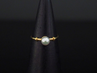 Vente aux enchères Petite bague en or jaune, sertie en son centre d'une perle blanche.  T