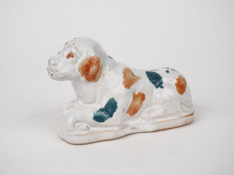 Vente aux enchères Tirelire en faïence polychrome en forme de chien assis. Dim. 9 x 14 x 