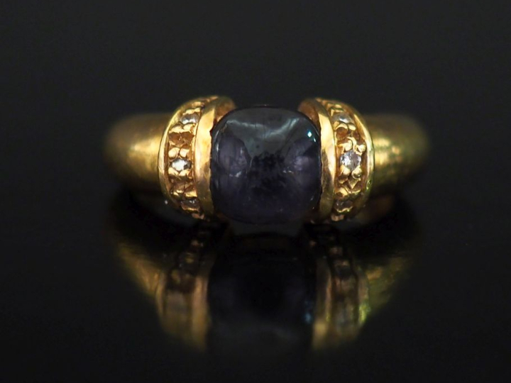 Bague en or jaune 750, sertie en son centre d'une pierre bleue en cabo