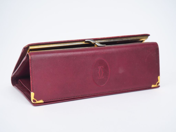CARTIER,  Porte-feuilles en cuir bordeaux.  Signé.  10 x 19 cm (petite