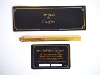 Vente aux enchères CARTIER, Must Stylo bille en plaqué or, à décor de cannelures.  Signé.
