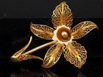 Vente aux enchères Broche en or jaune 750 en forme de fleur, à décor ajouré et filigrané.