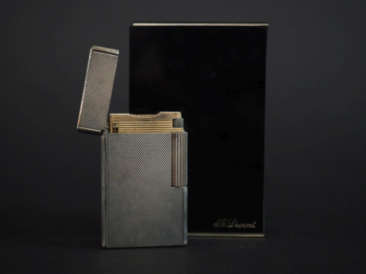DUPONT Briquet eun métal argenté, à décor guilloché.  H. 5,8 cm Signé.