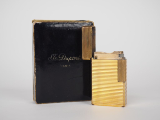 Vente aux enchères DUPONT Briquet en métal doré, à décor de cannelures.  Signé.  Dans sa 