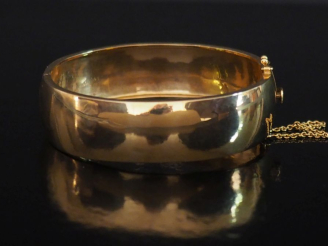 Vente aux enchères Large bracelet jonc en or jaune 750.  Chainette de sécurité en or jaun