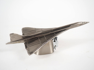 Vente aux enchères Briquet en métal argenté figurant le Concorde. Dim. 7,5 x 23 cm.