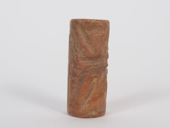 Orient ancien. Sceau cylindre en pierre rouge orné de traits formant d