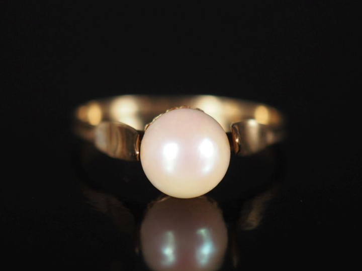 Petite bague en or jaune 750, sertie en son centre d'une perle.  TDD. 