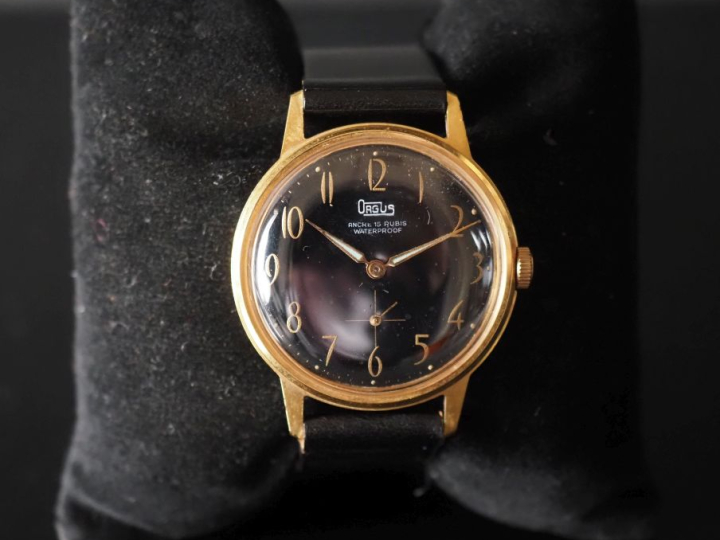 ORGUS Montre bracelet en métal doré.  Cadran rond à fond noir, chiffre