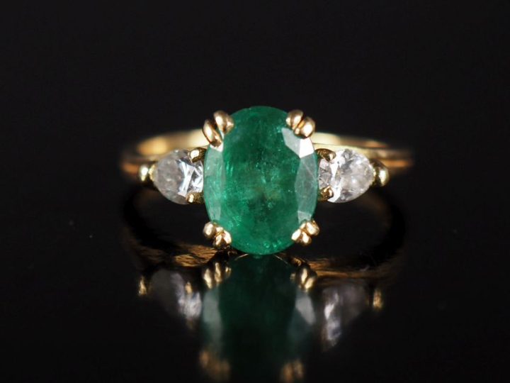 Bague en or jaune 750, serte en son centre d'une émeraude épaulée de d