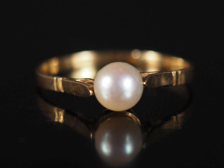 Bague en or jaune 750, sertie en son centre d'une perle blanche.  TDD.