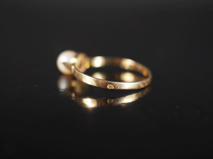 Bague en or jaune 750, sertie en son centre d'une perle blanche.  TDD.
