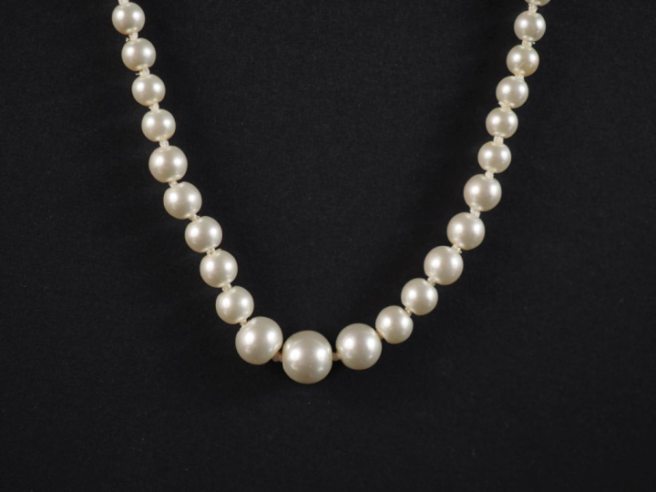 Collier de perles blanches disposées en chute.  Fermoir en métal doré.