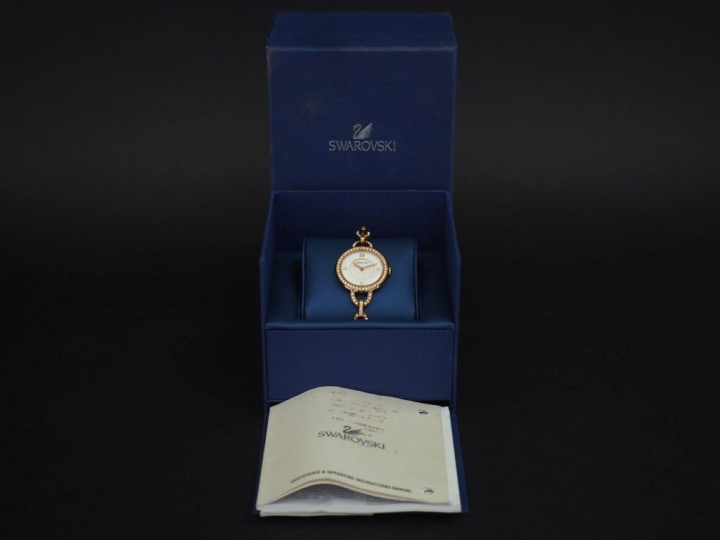 SWAROVSKI Montre bracelet de dame en métal doré, rehaussé sur le cadra