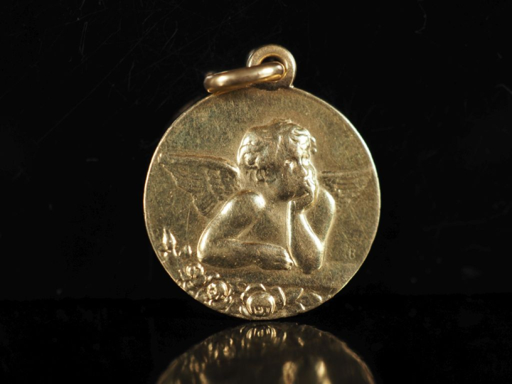 Médaille en or jaune 750, figurant un angelot.  Diam. 1,8 cm Poids. 3,