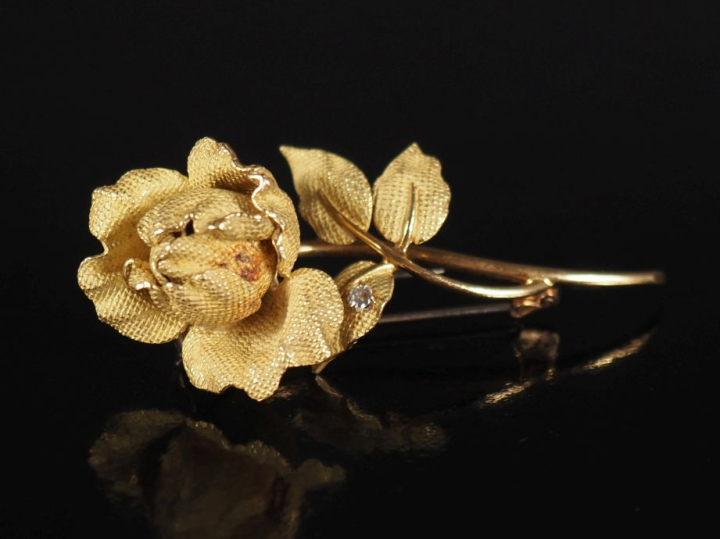 Broche en or jaune 750, en forme de rose agrémentée d’un diamant sur u