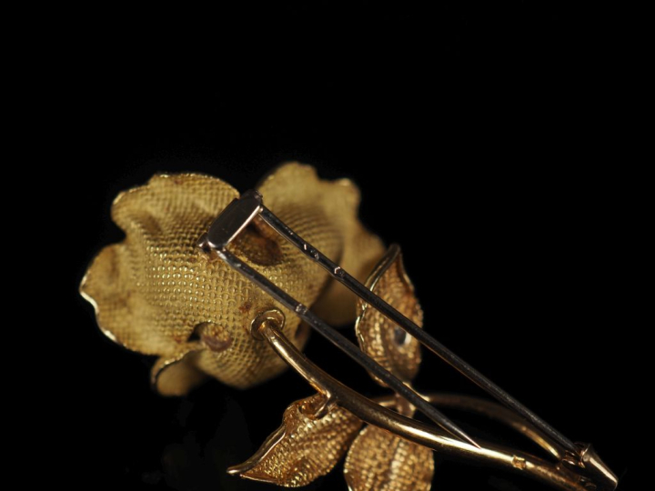 Broche en or jaune 750, en forme de rose agrémentée d’un diamant sur u