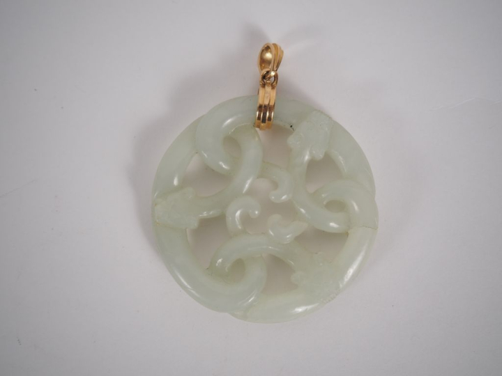 Pendentif en jade blanc à décor ajouré de têtes de dragon. Diam. 5,5 c