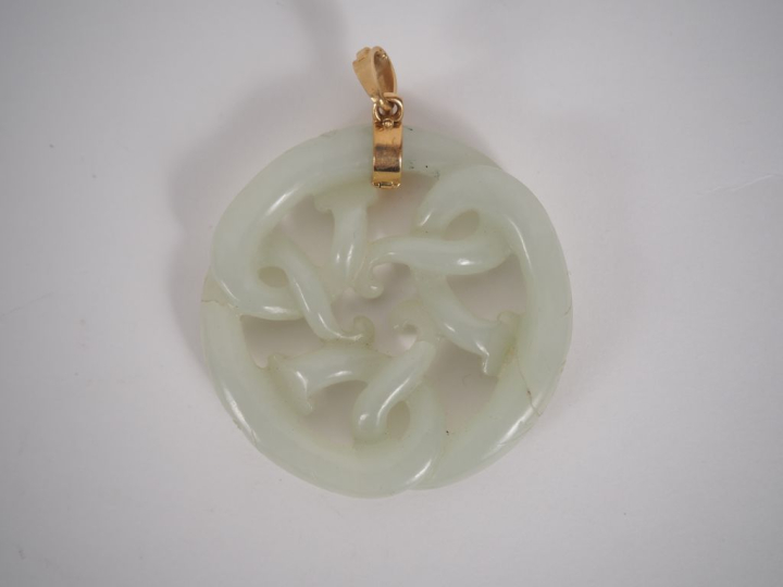 Pendentif en jade blanc à décor ajouré de têtes de dragon. Diam. 5,5 c