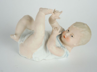 Vente aux enchères Sujet 1900 en biscuit polychrome 'bébé couché'. 15 x 22,5 cm