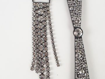 SONIA RYKIEL. Broche en métal et strass figurant un nœud papillon asym