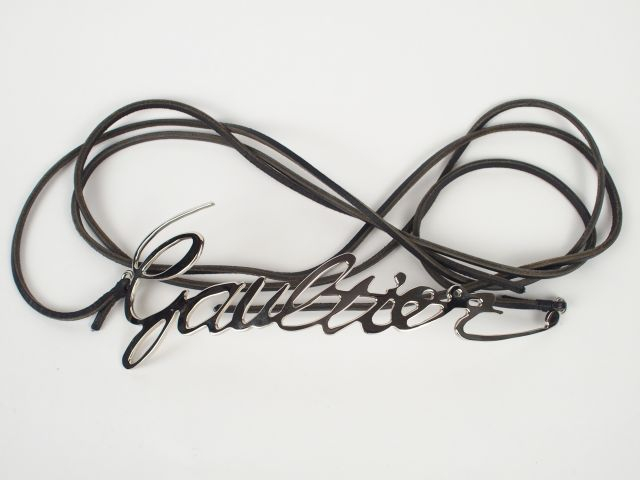 JEAN PAUL GAUTIER. Ceinture en métal argenté et cordons en cuir noir. 